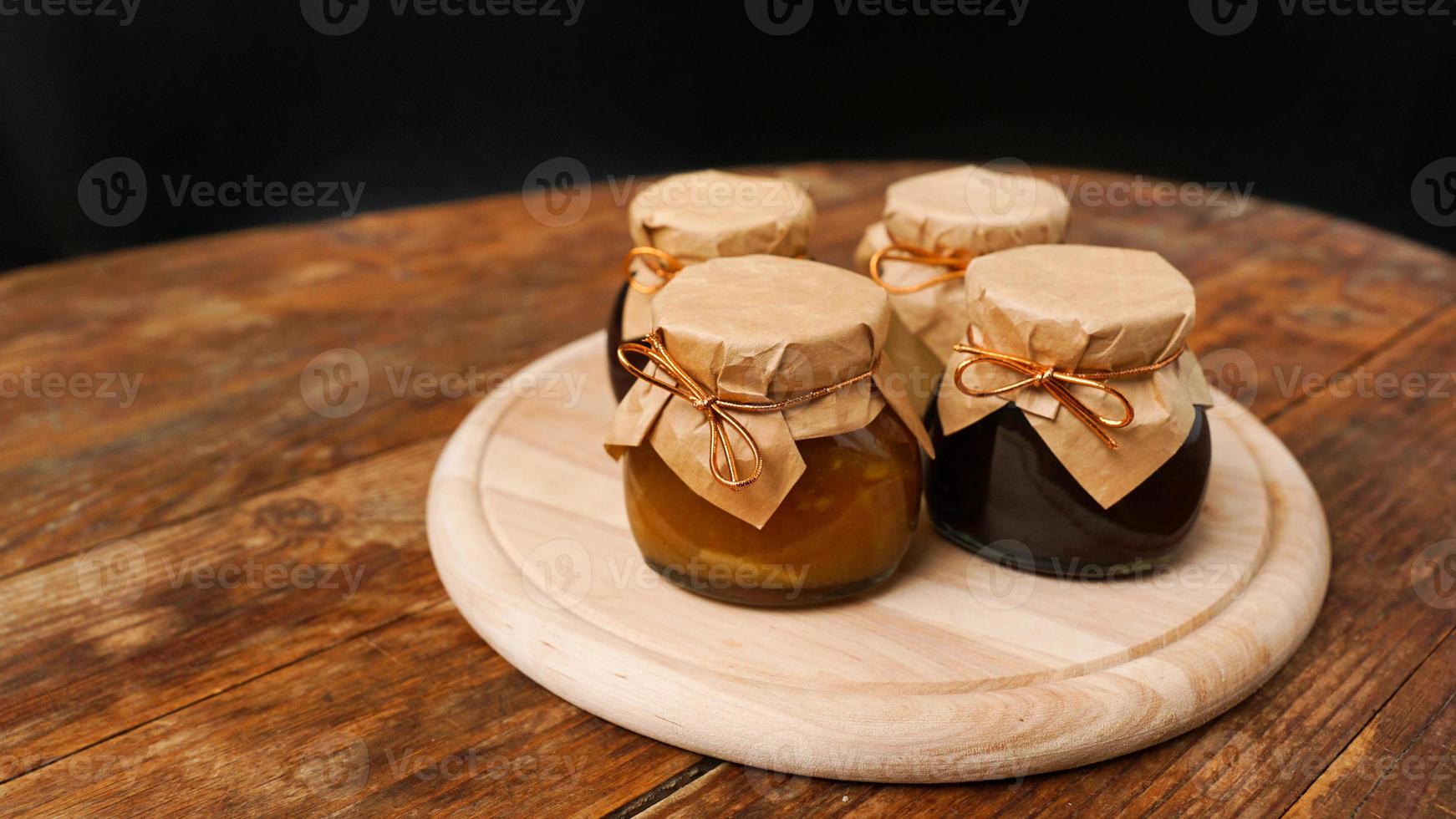 Four glass jars with different kinds of jam on wooden table. Homemade jam photo