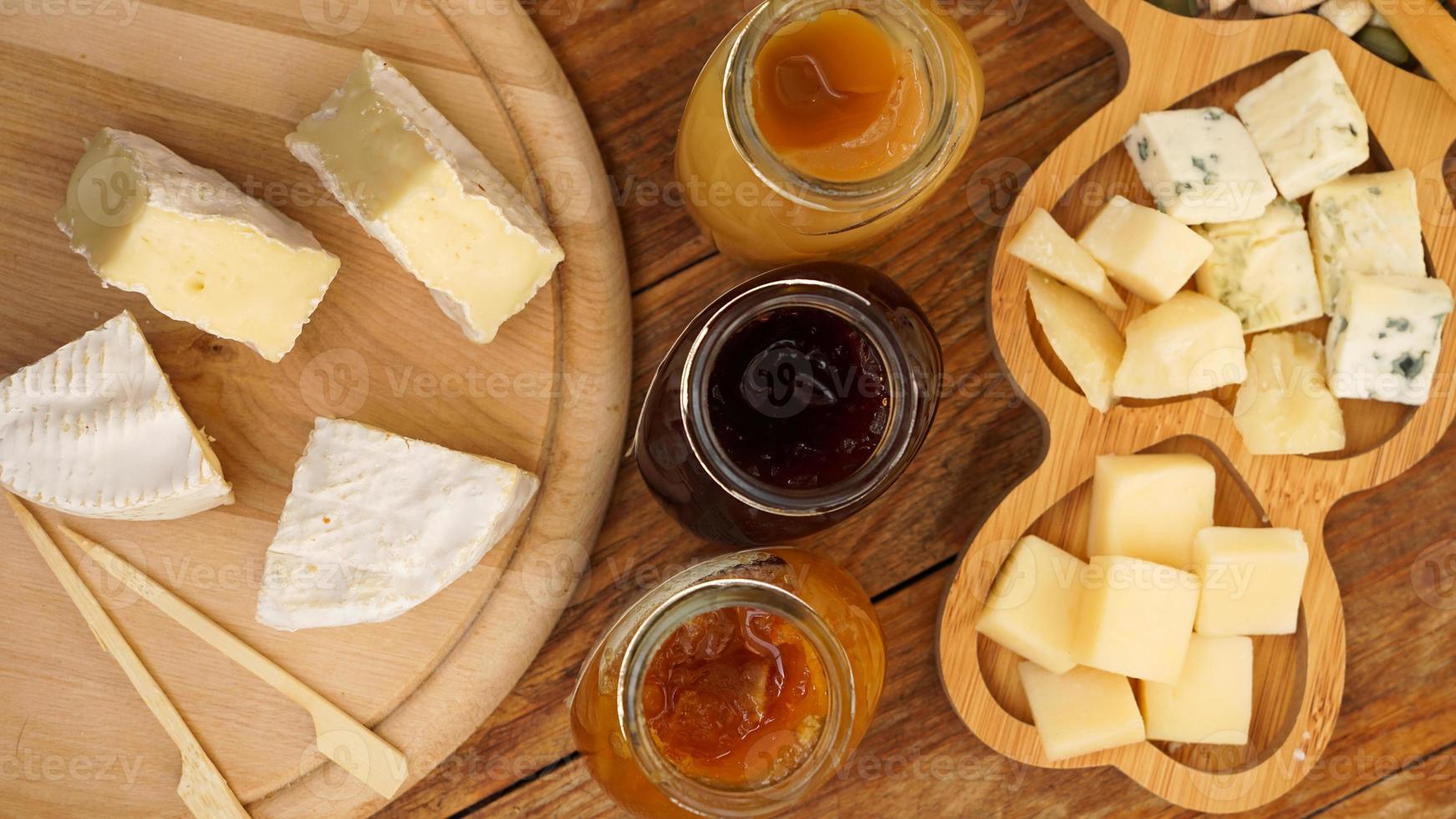 tarros de mermeladas caseras y una variedad de quesos sobre una mesa de madera. plato de queso foto