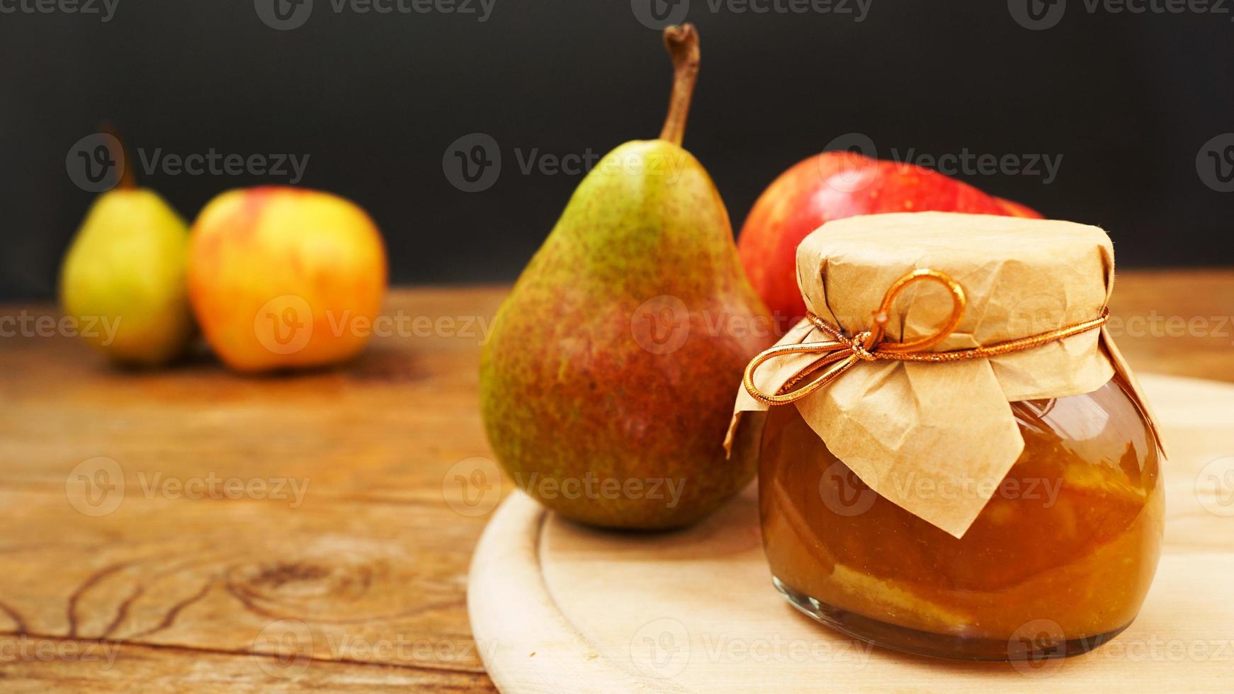 frasco de vidrio de mermelada casera de pera y manzana con frutas frescas en la mesa foto