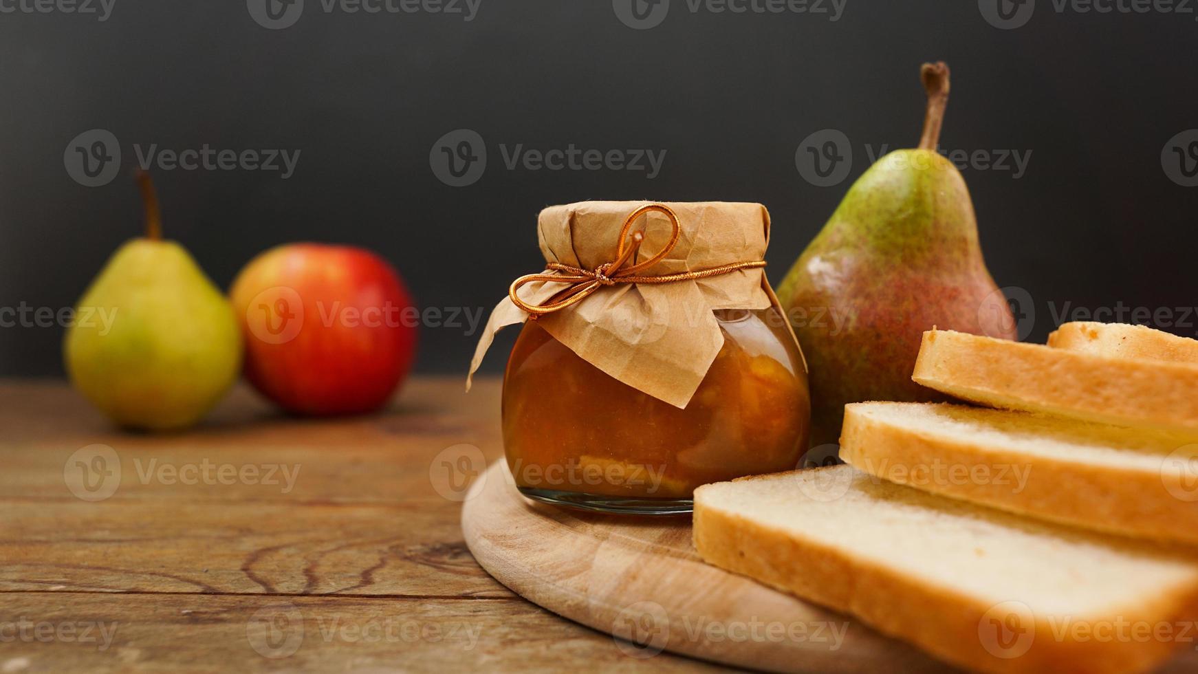 Glass jar of homemade pear and apple jam with fresh fruits on the table photo