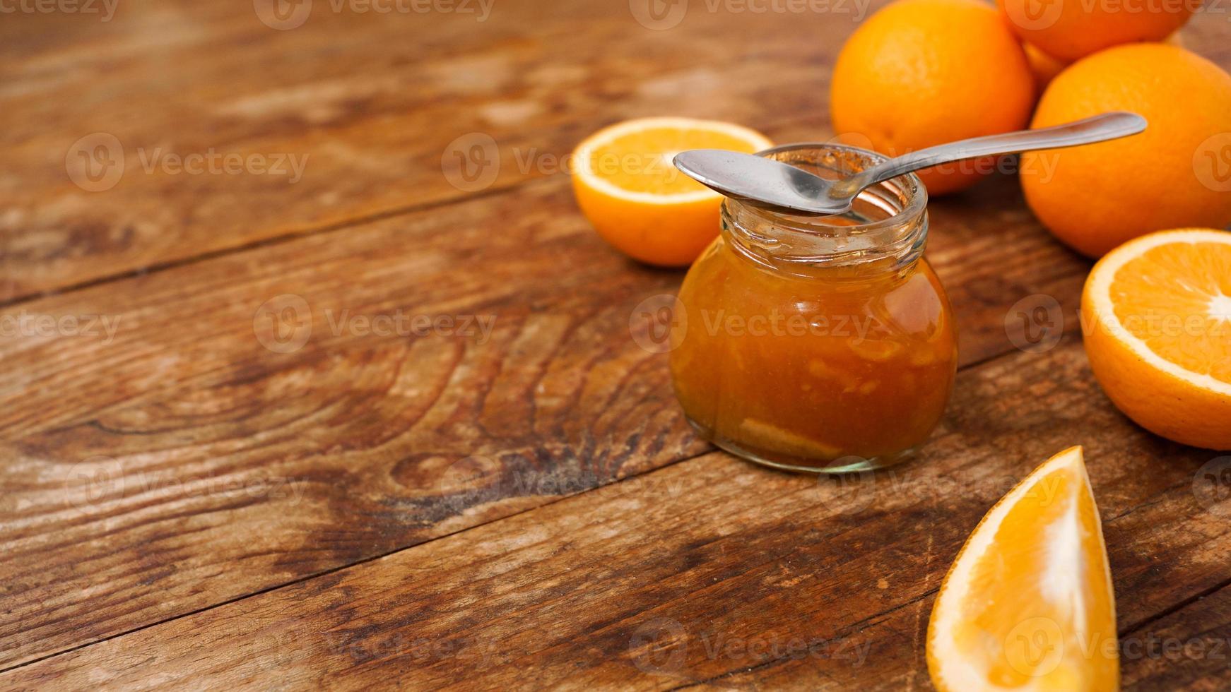 Jar of orange jam on wooden background from top view. Place for text. photo