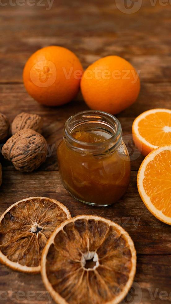 Sweet orange jam or marmalade dessert with walnuts on wooden background photo
