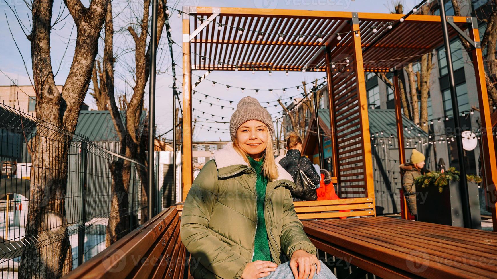 Smiling blonde woman sitting at a table in an urban space street cafe photo
