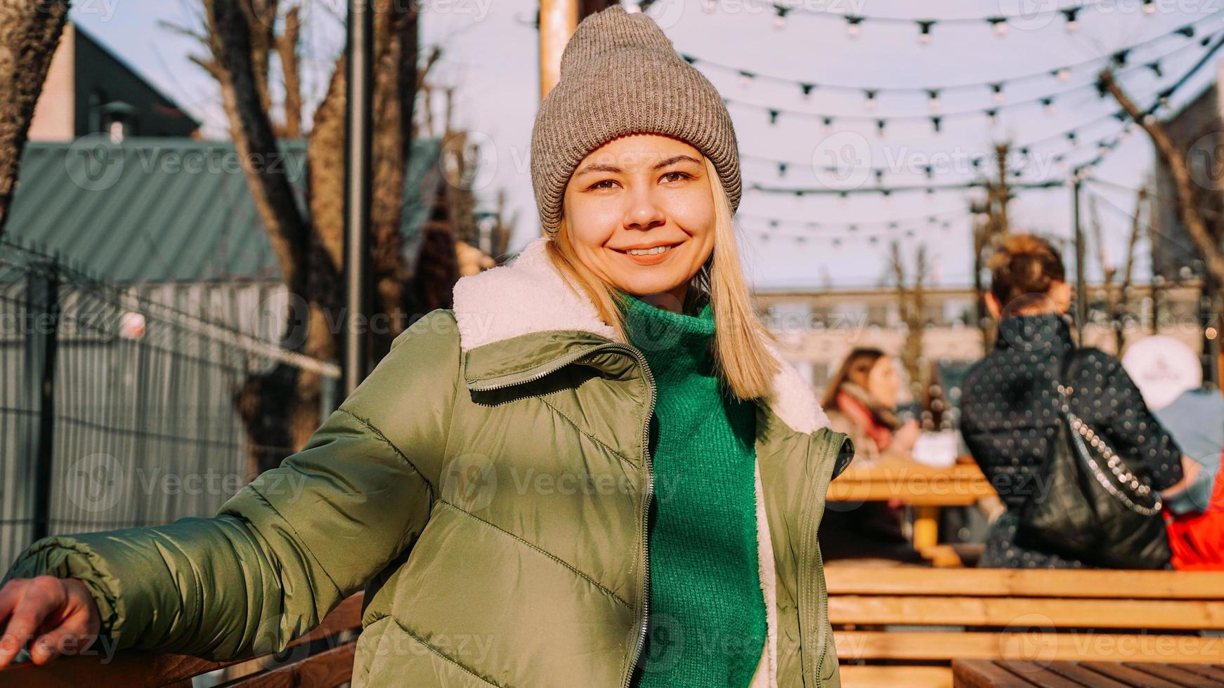 Smiling blonde woman sitting at a table in an urban space street cafe photo