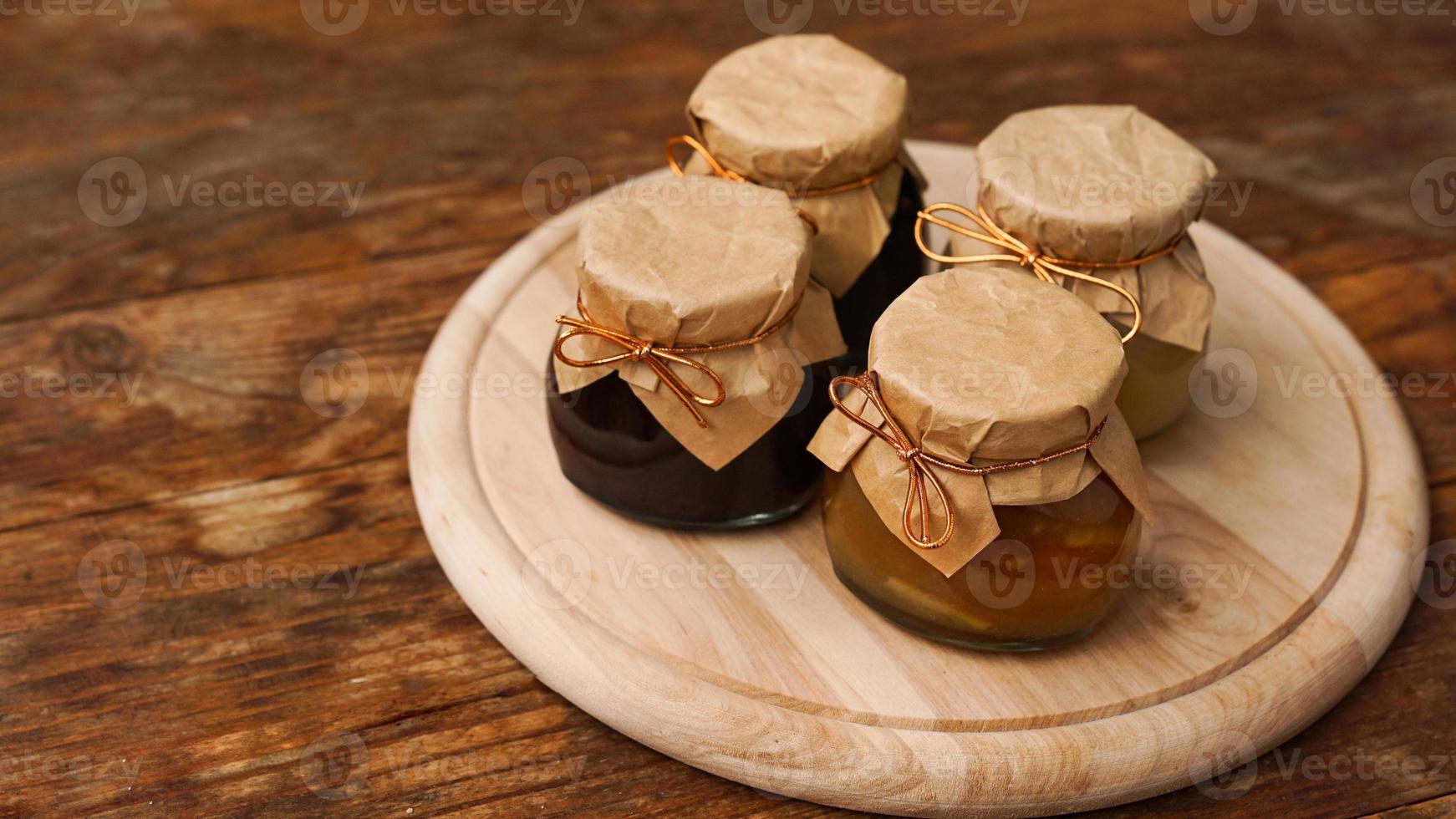 Four glass jars with different kinds of jam on wooden table. Homemade jam photo