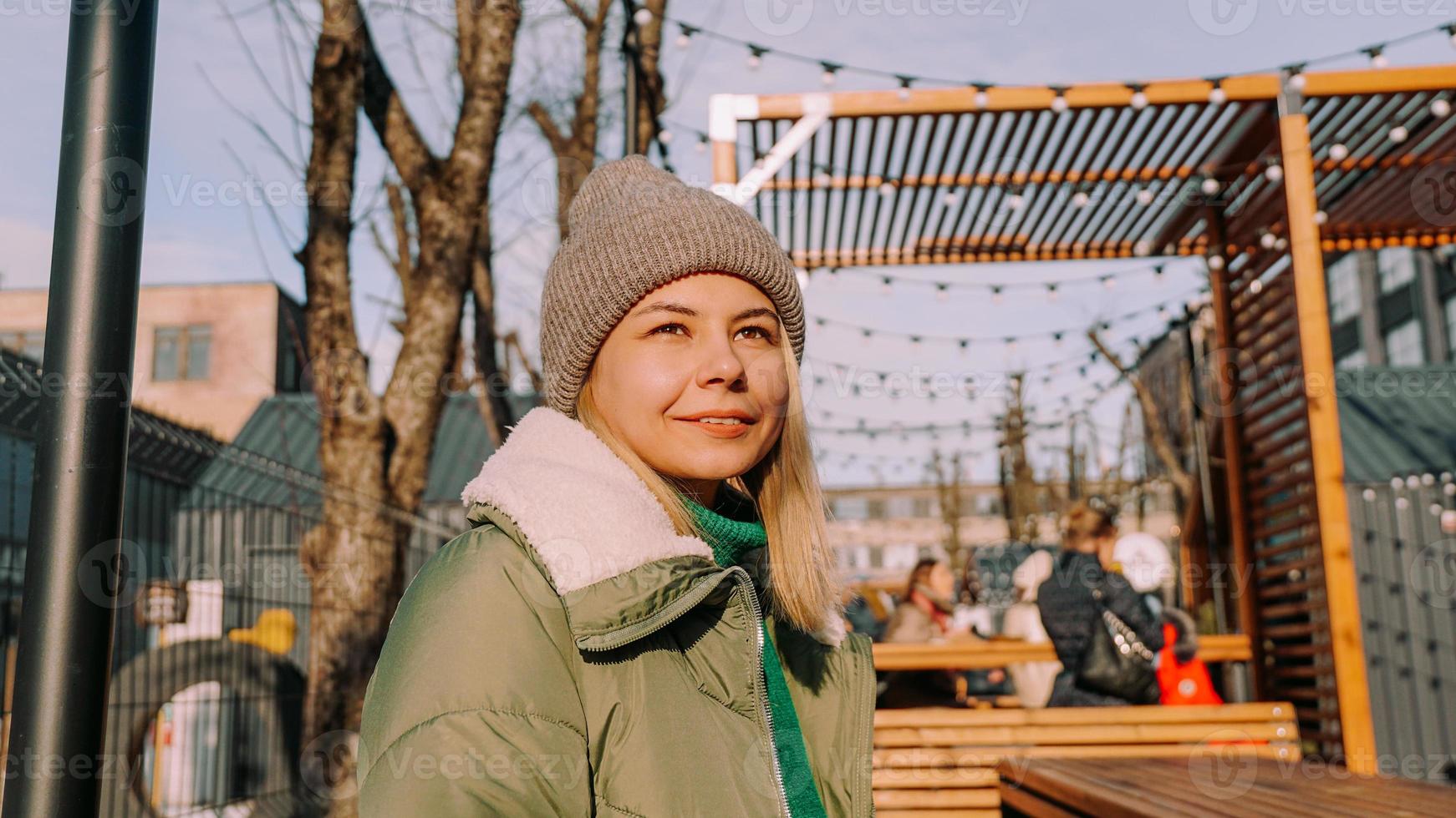 Smiling blonde woman sitting at a table in an urban space street cafe photo