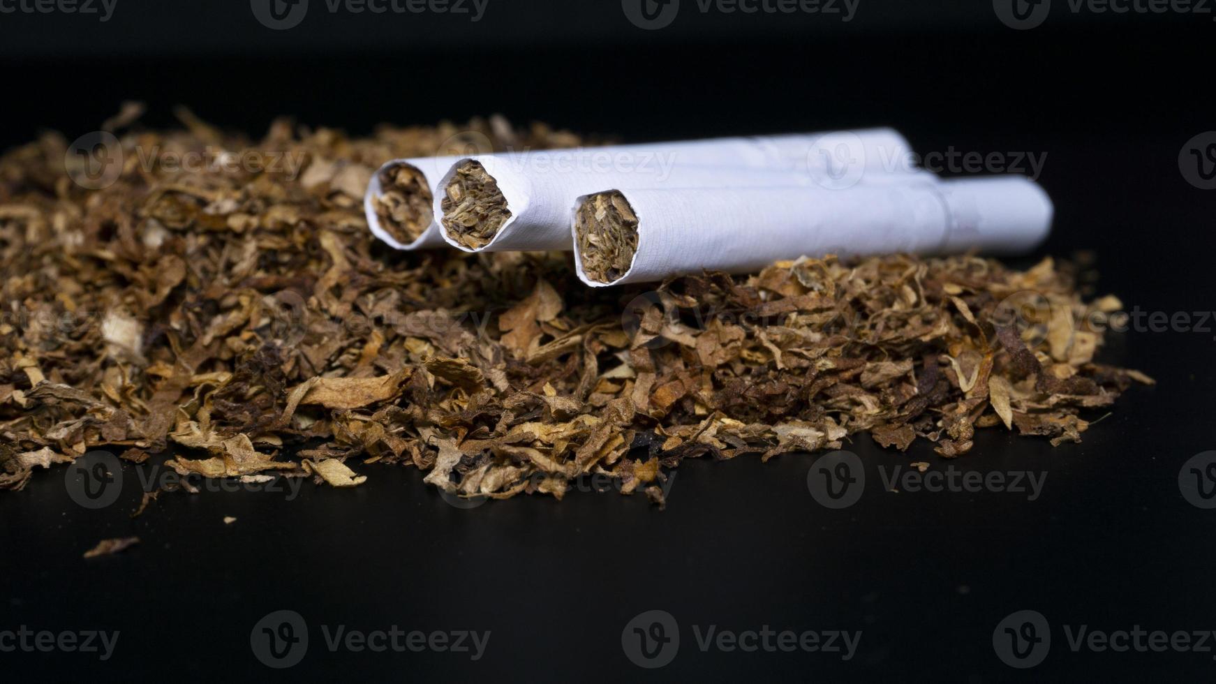 Pile of tobacco and some cigarette on a black background photo