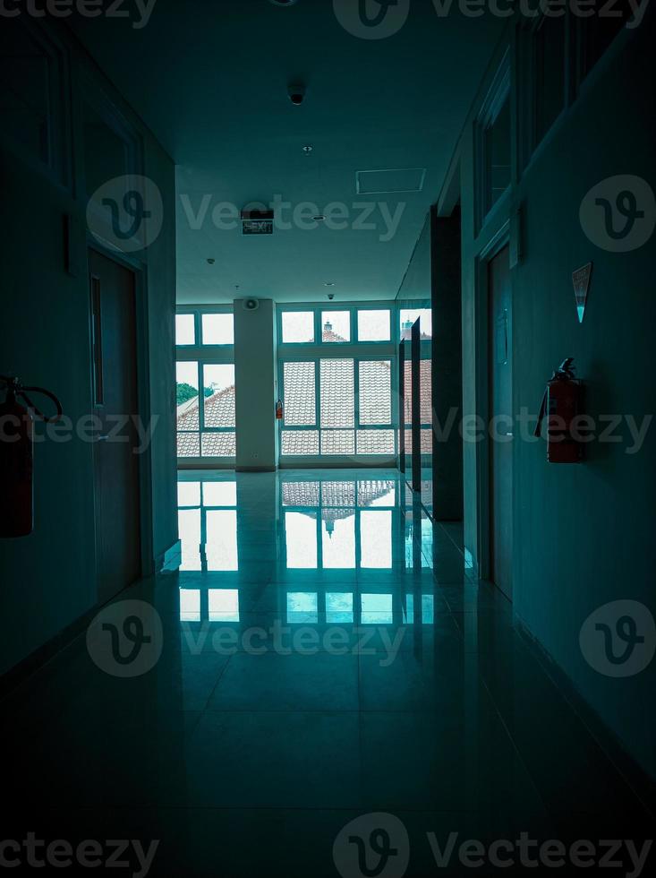 Office corridor with a tense and silent and horror atmosphere and nobody. Dark blue effect. Windows and glass. photo