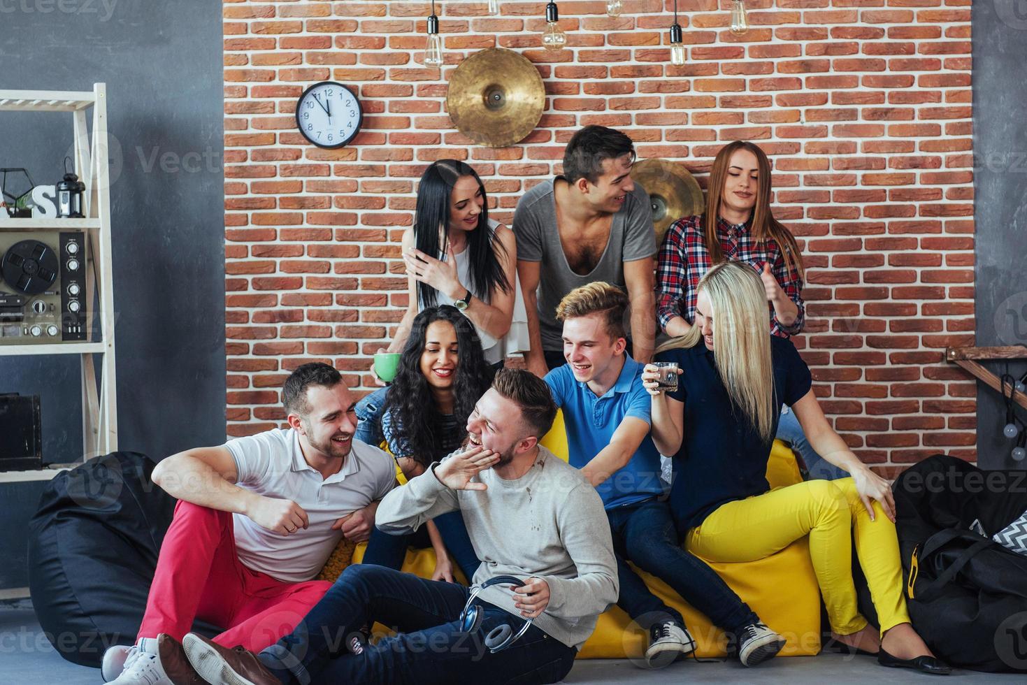 Group portrait of multi-ethnic boys and girls with colorful fashionable clothes holding friend posing on a brick wall, Urban style people having fun, Concepts about youth togetherness lifestyle photo