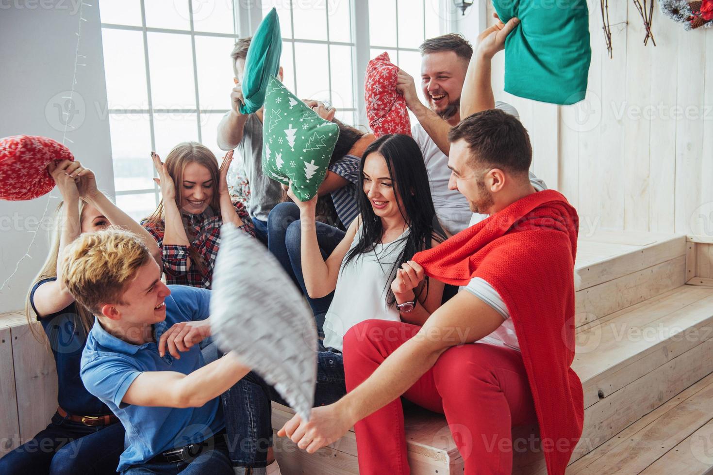 Crazy young best friends fighting pillows at home. Mixed race group of people. Concept  entertainment and lifestyle photo