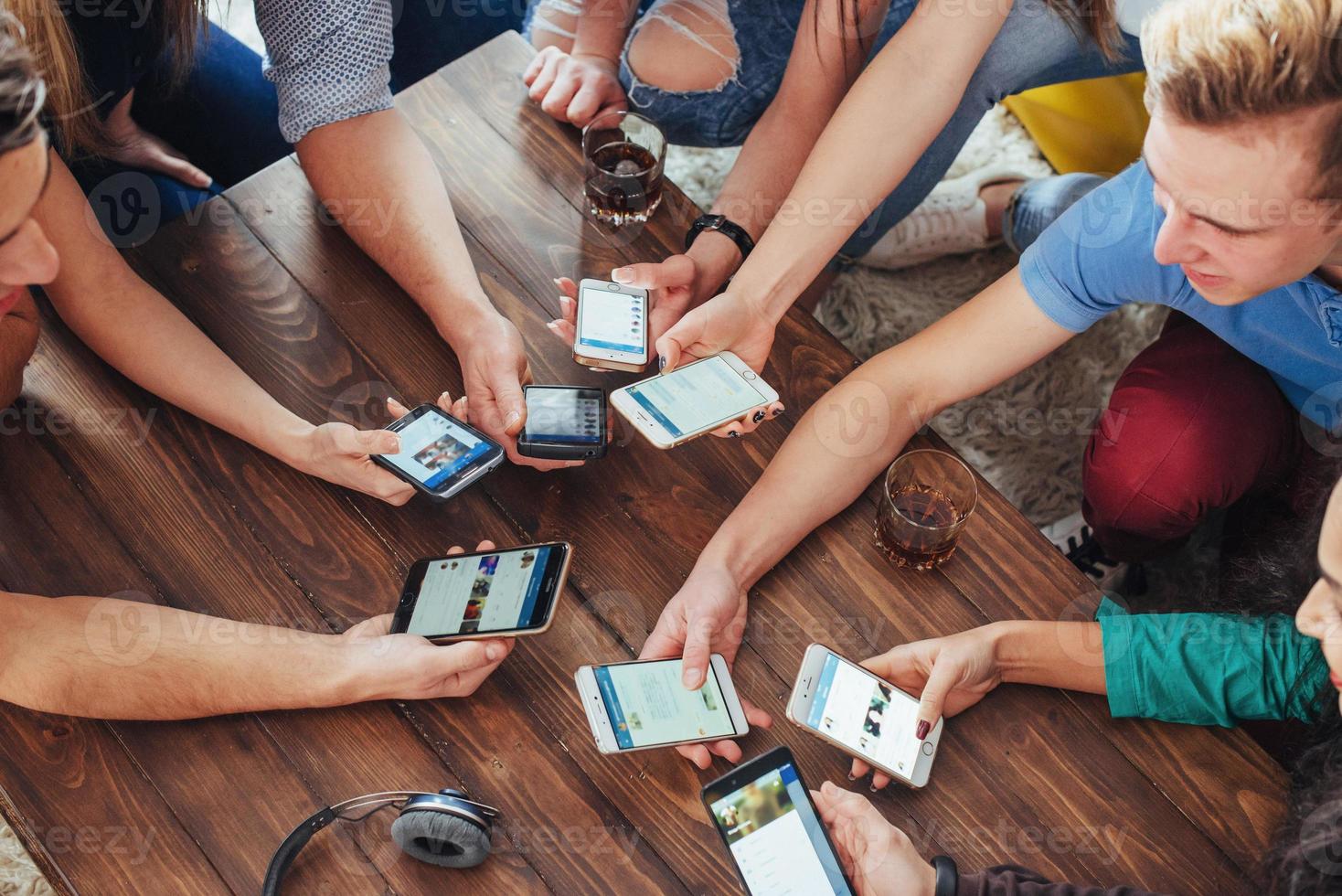 Top view hands circle using phone in cafe - Multiracial friends mobile addicted interior scene from above - Wifi connected people in bar table meeting - Concept of teamwork photo