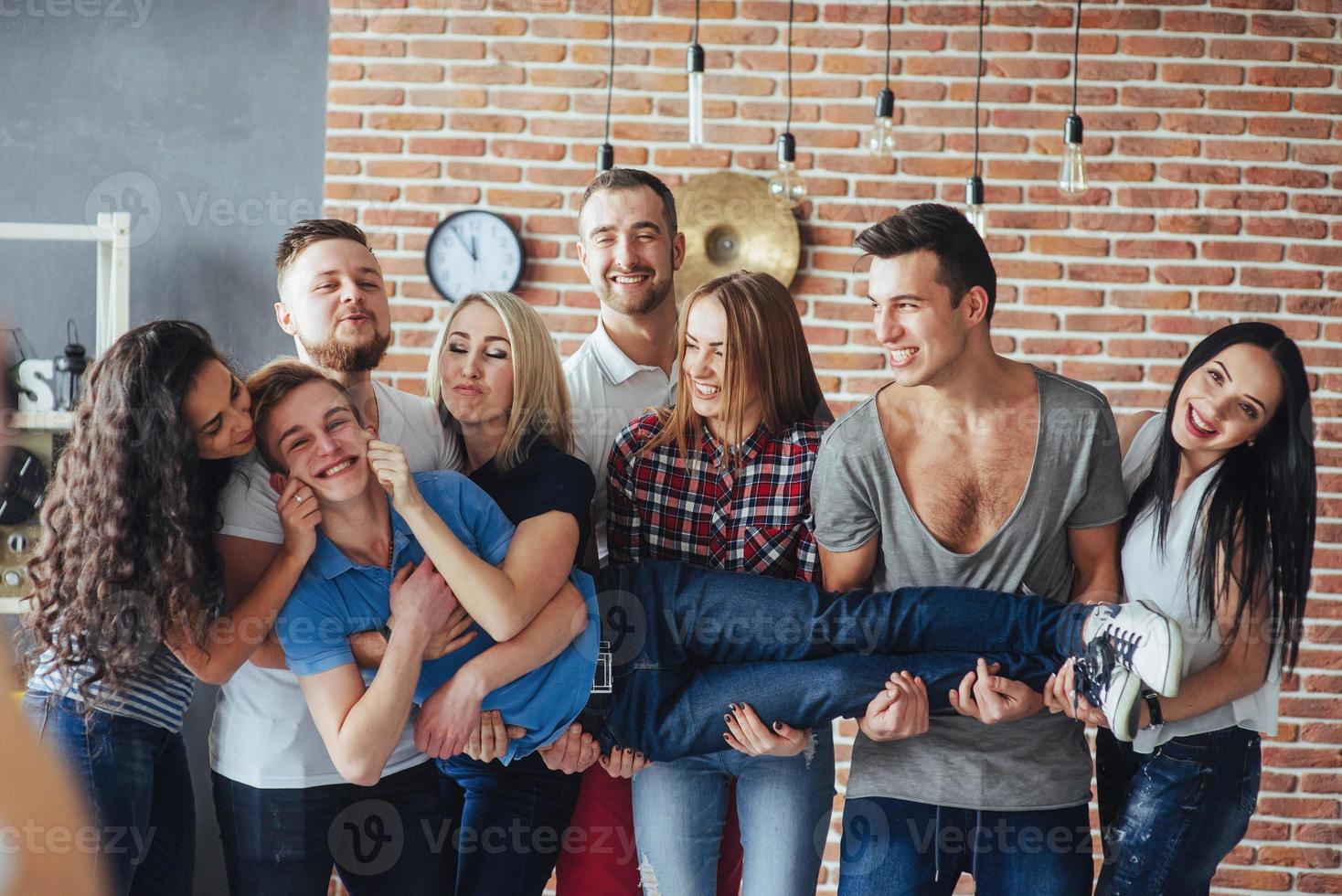 Group portrait of multi-ethnic boys and girls with colorful fashionable clothes holding friend  posing on a brick wall, Urban style people having fun, Concepts about youth  togetherness lifestyle photo