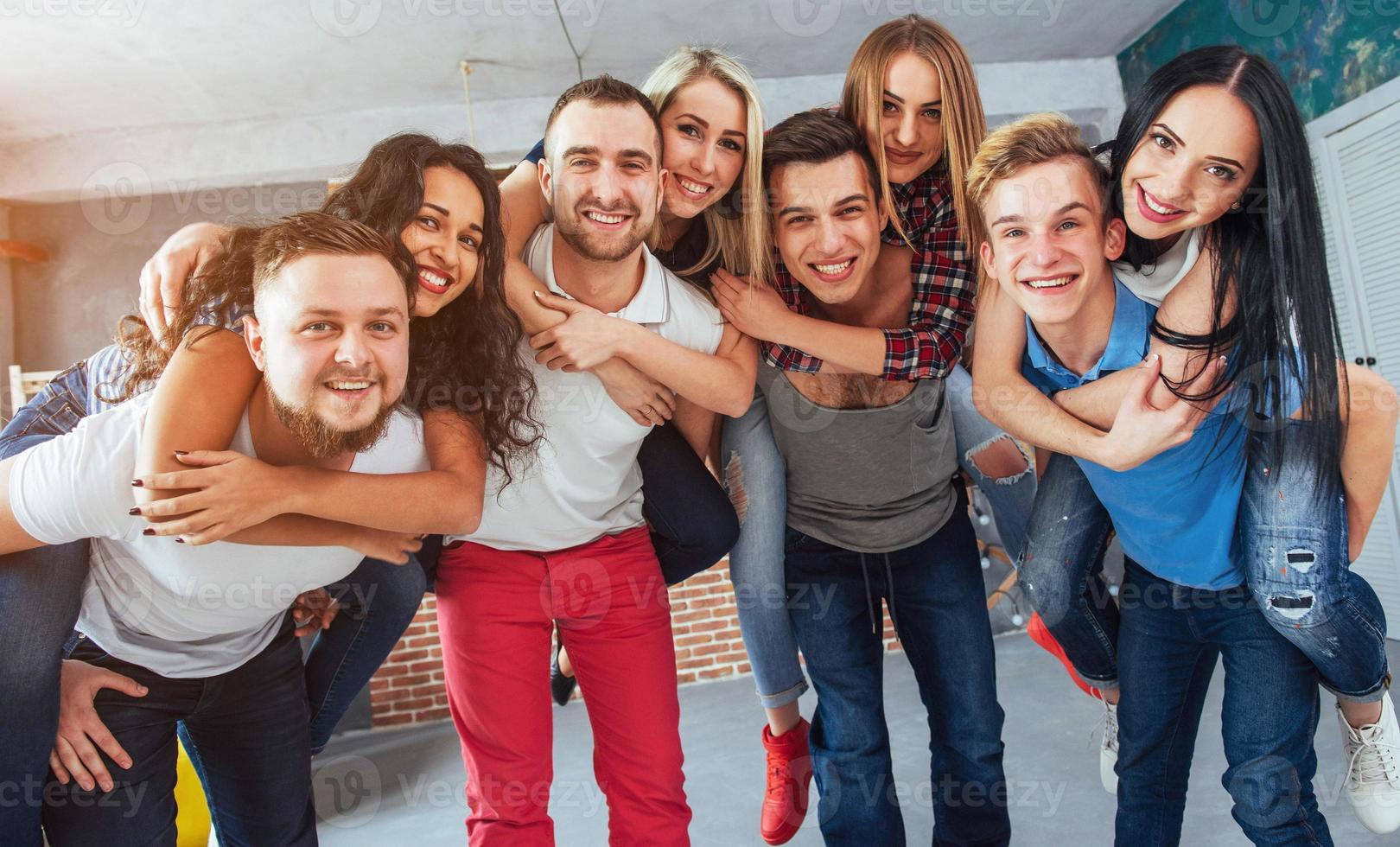 retrato grupal de niños y niñas multiétnicos con ropa colorida de moda sosteniendo a un amigo posando en una pared de ladrillo, gente de estilo urbano divirtiéndose, conceptos sobre el estilo de vida de la unión juvenil foto