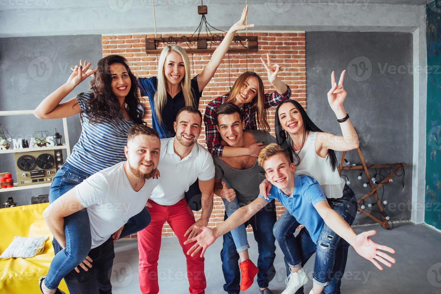 Group portrait of multi-ethnic boys and girls with colorful fashionable clothes holding friend posing on a brick wall, Urban style people having fun, Concepts about youth togetherness lifestyle photo