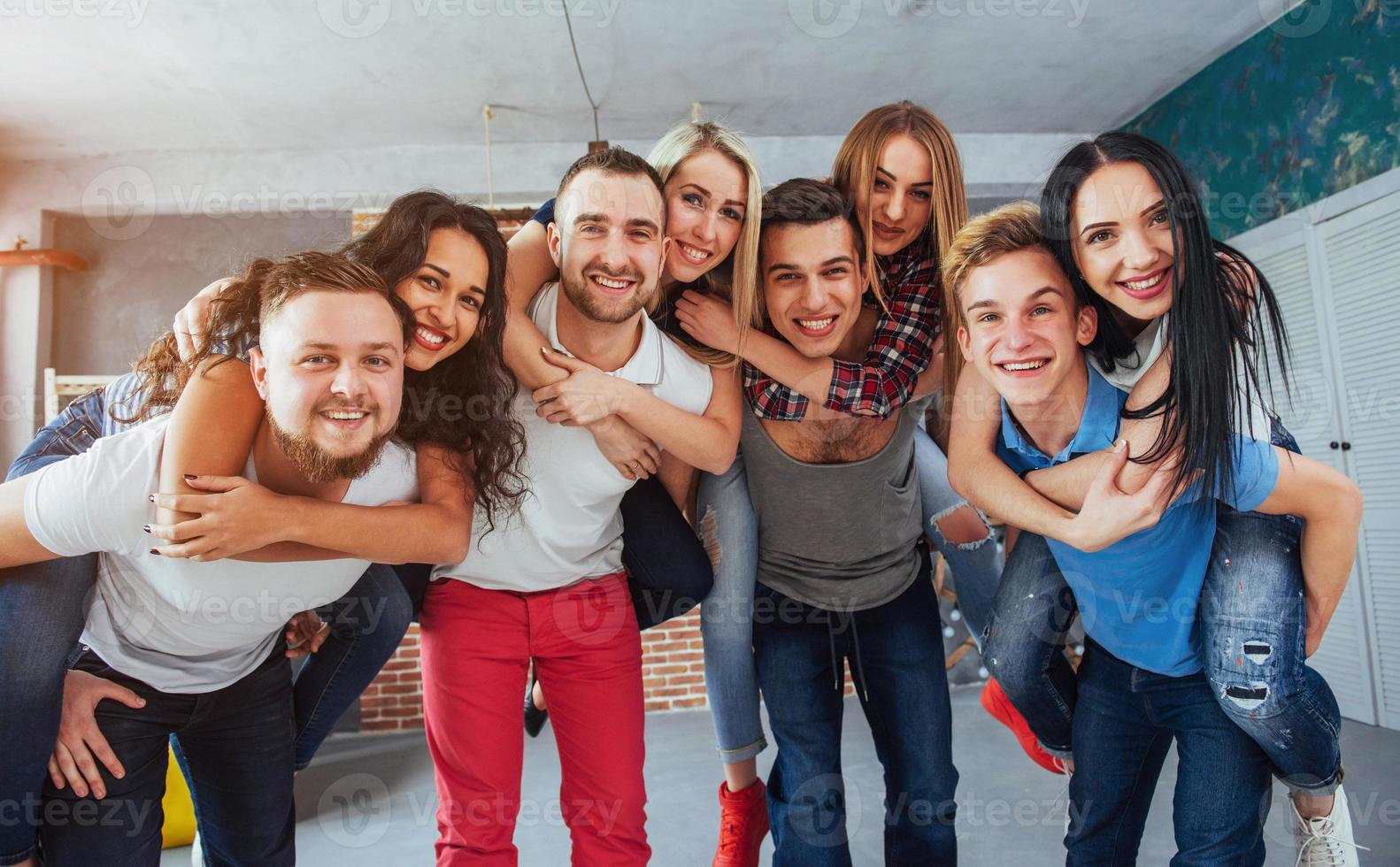 Group portrait of multi-ethnic boys and girls with colorful fashionable clothes holding friend posing on a brick wall, Urban style people having fun, Concepts about youth togetherness lifestyle photo