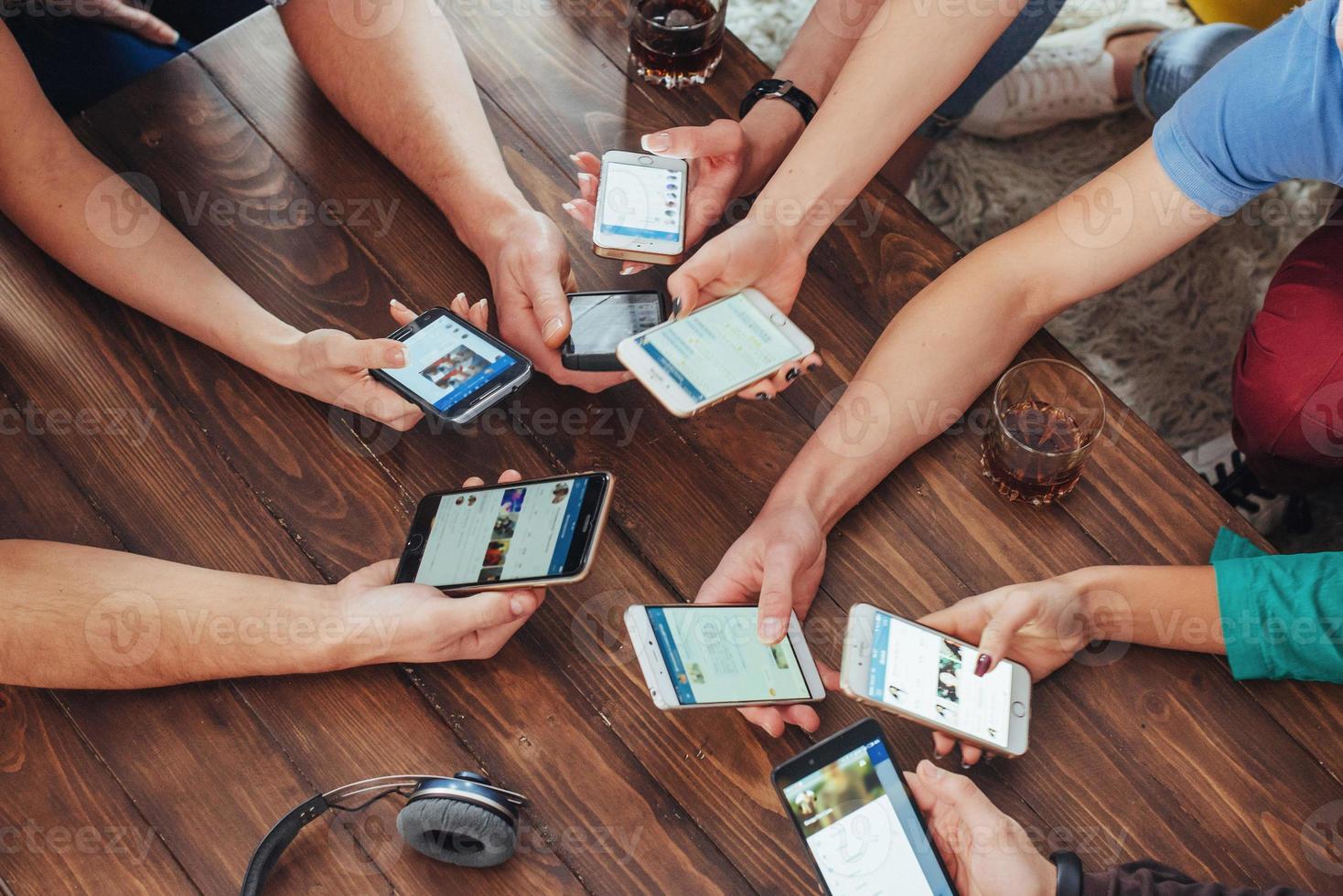 Top view hands circle using phone in cafe - Multiracial friends mobile addicted interior scene from above - Wifi connected people in bar table meeting - Concept of teamwork photo