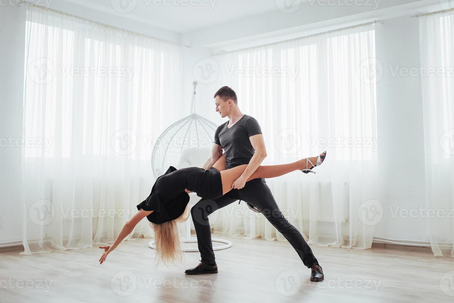 Young couple dancing latin music. Bachata, merengue, salsa. Two elegance pose on white room photo