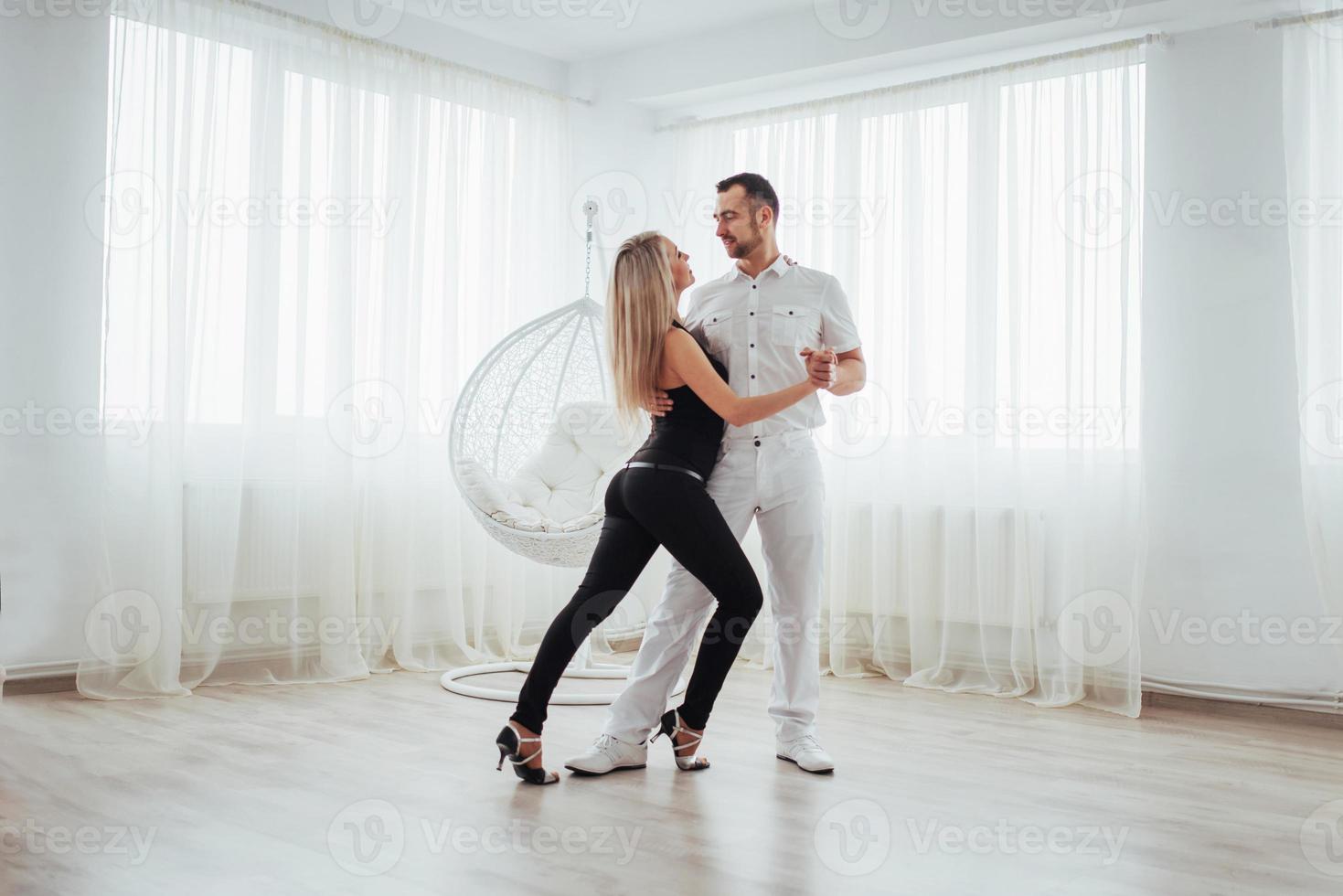 Young couple dancing latin music Bachata, merengue, salsa. Two elegance pose on white room photo