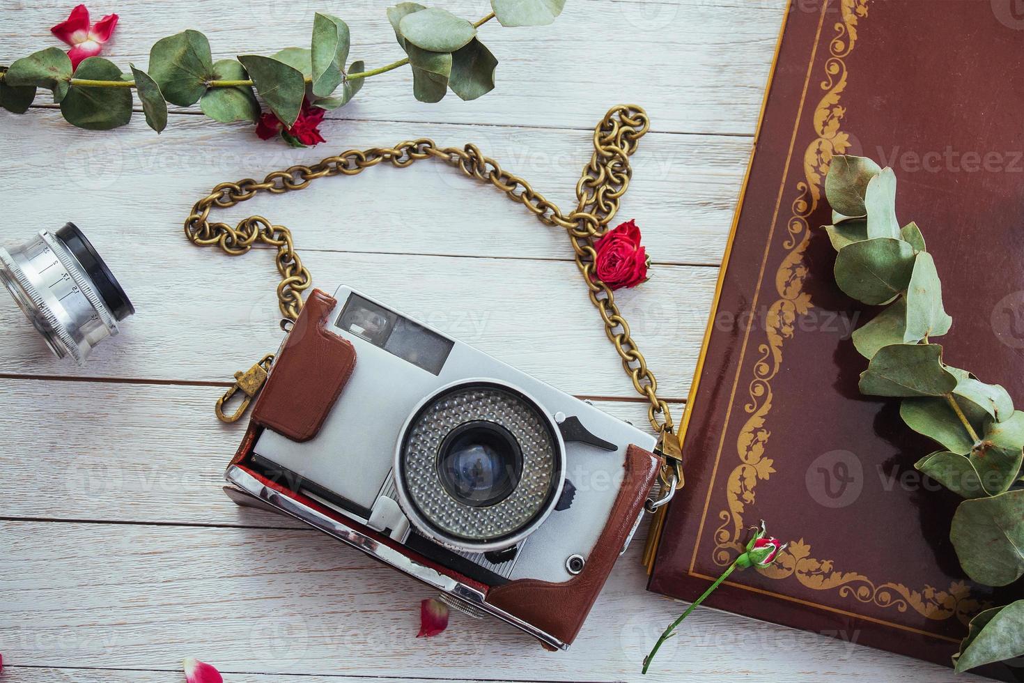 rollo de cámara retro película fotográfica y flores sobre fondo blanco de madera foto