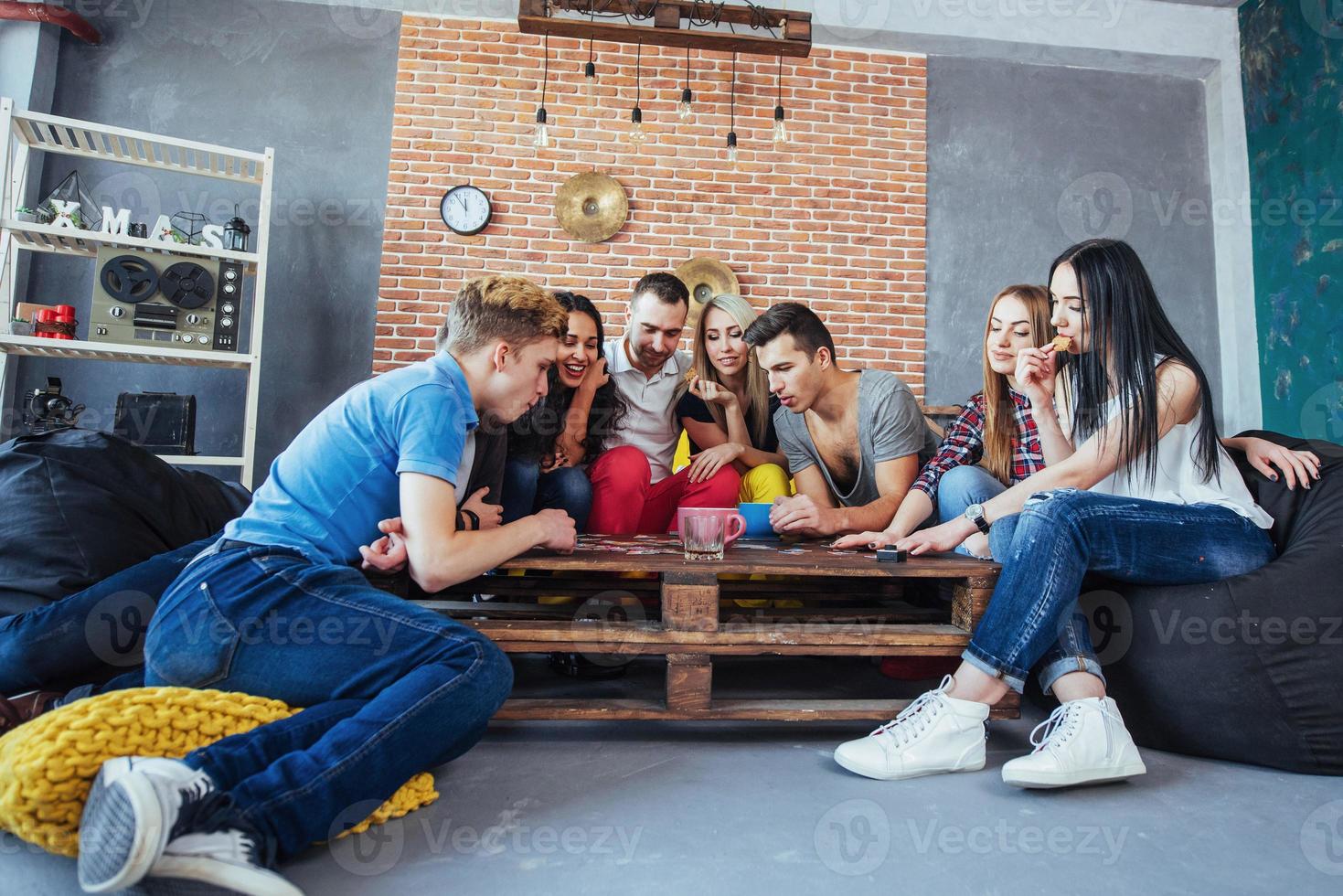 Group of creative friends sitting at wooden table. People having fun while playing board game photo