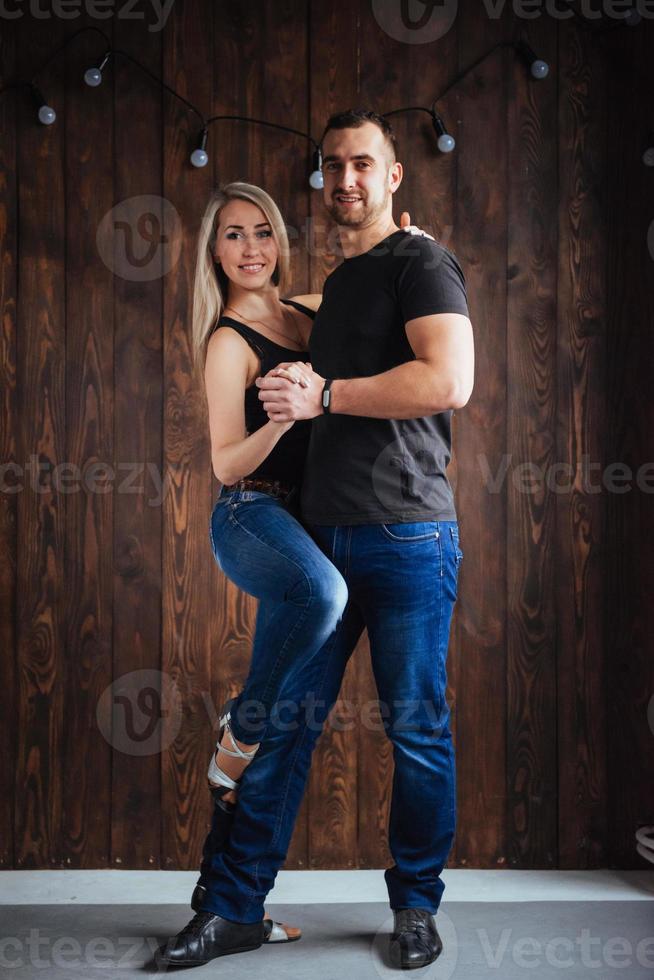 Young couple dancing latin music Bachata, merengue, salsa. Two elegance pose on cafe with brick walls photo