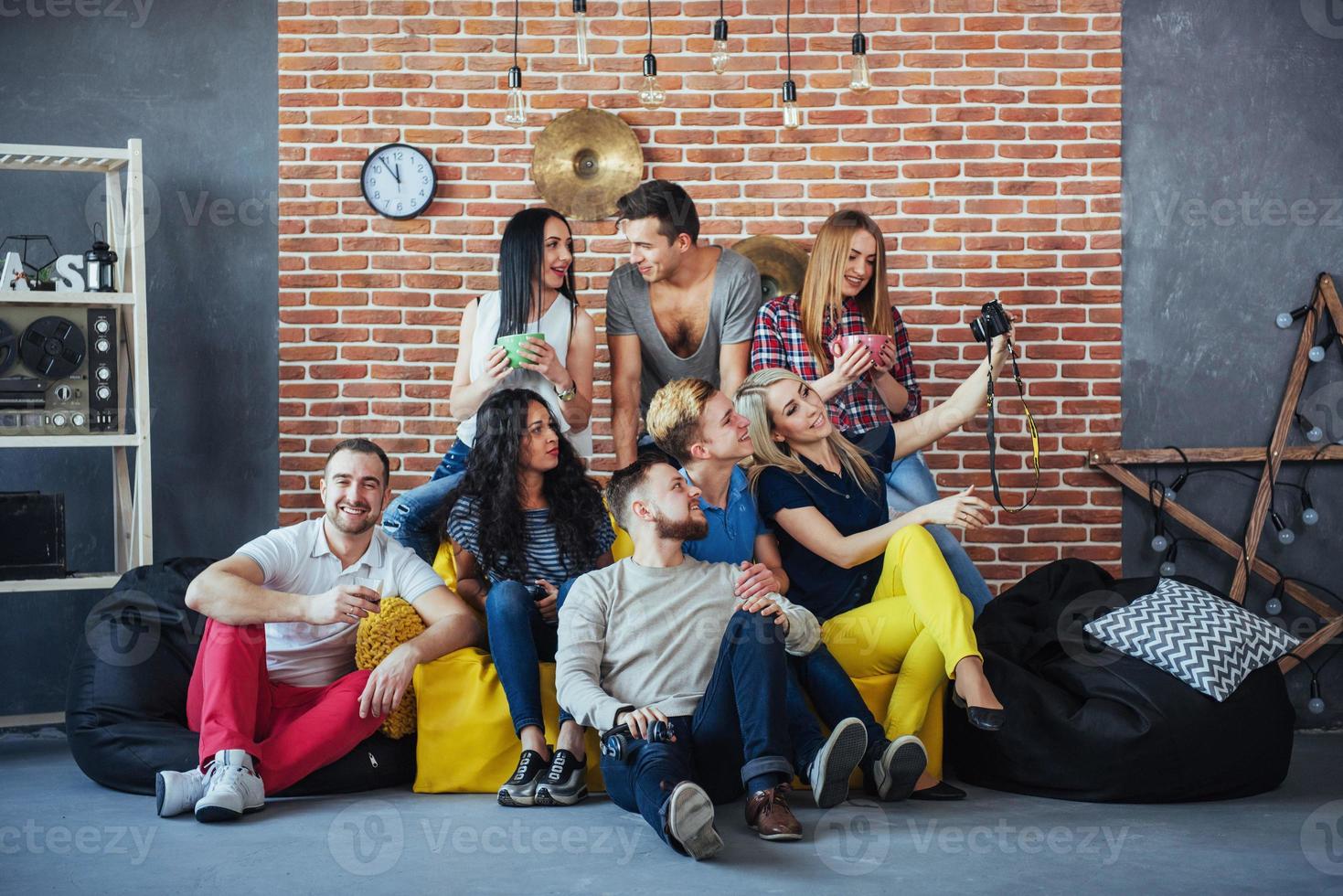 Group portrait of multi-ethnic boys and girls with colorful fashionable clothes holding friend posing on a brick wall, Urban style people having fun, Concepts about youth togetherness lifestyle photo