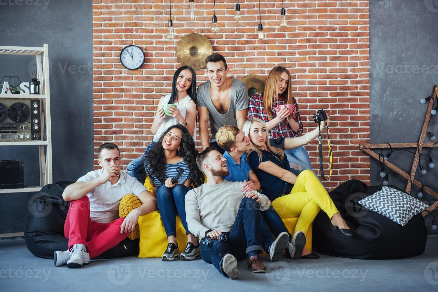 Group portrait of multi-ethnic boys and girls with colorful fashionable clothes holding friend posing on a brick wall, Urban style people having fun, Concepts about youth togetherness lifestyle photo