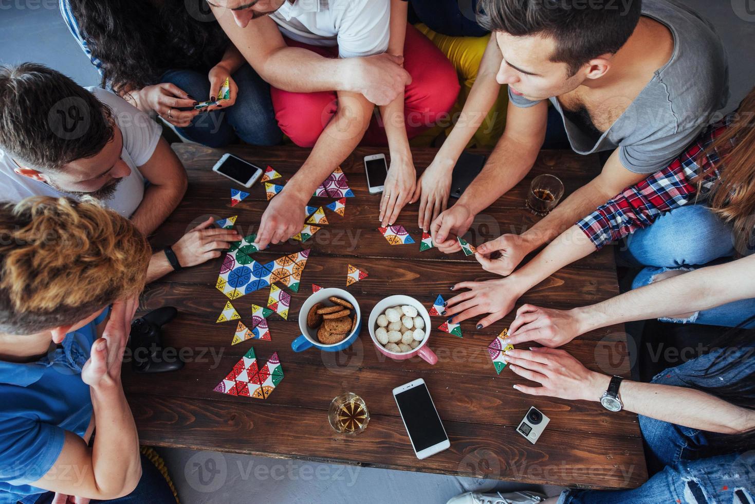 Top view creative photo of friends sitting at wooden table.  having fun while playing board game