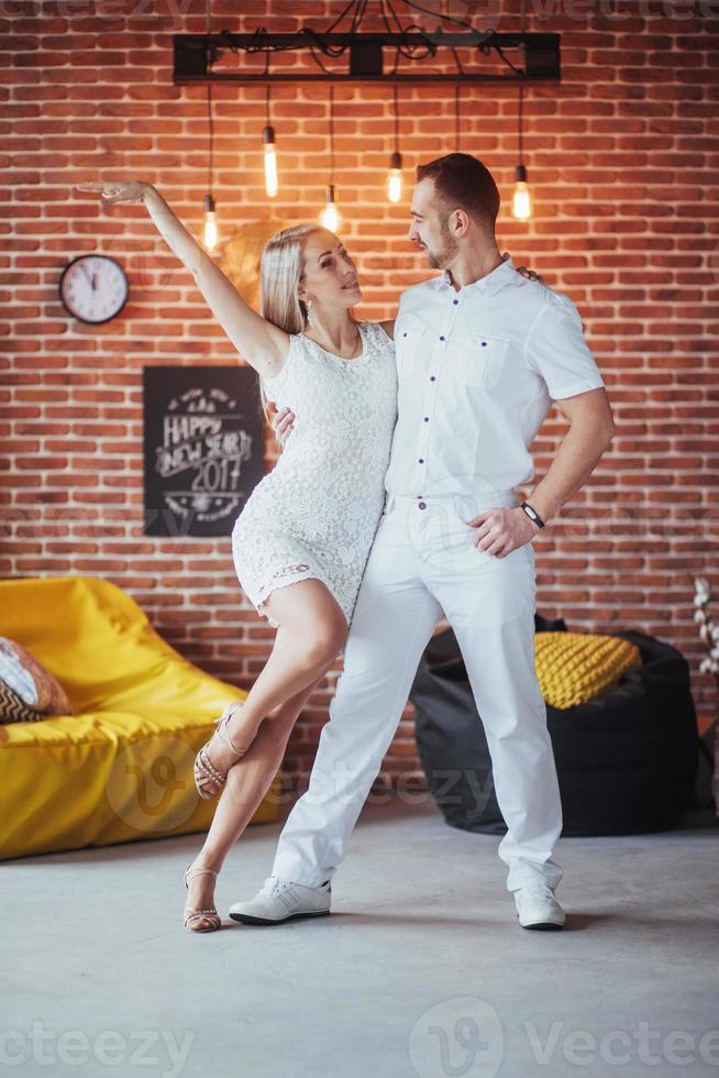 Young couple dancing latin music Bachata, merengue, salsa. Two elegance pose on cafe with brick walls photo