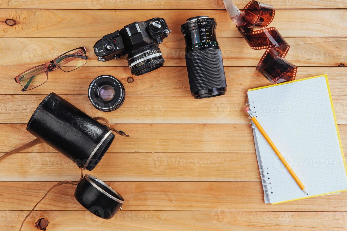 The old film camera and roll film and notebook with pencil on a wooden background photo