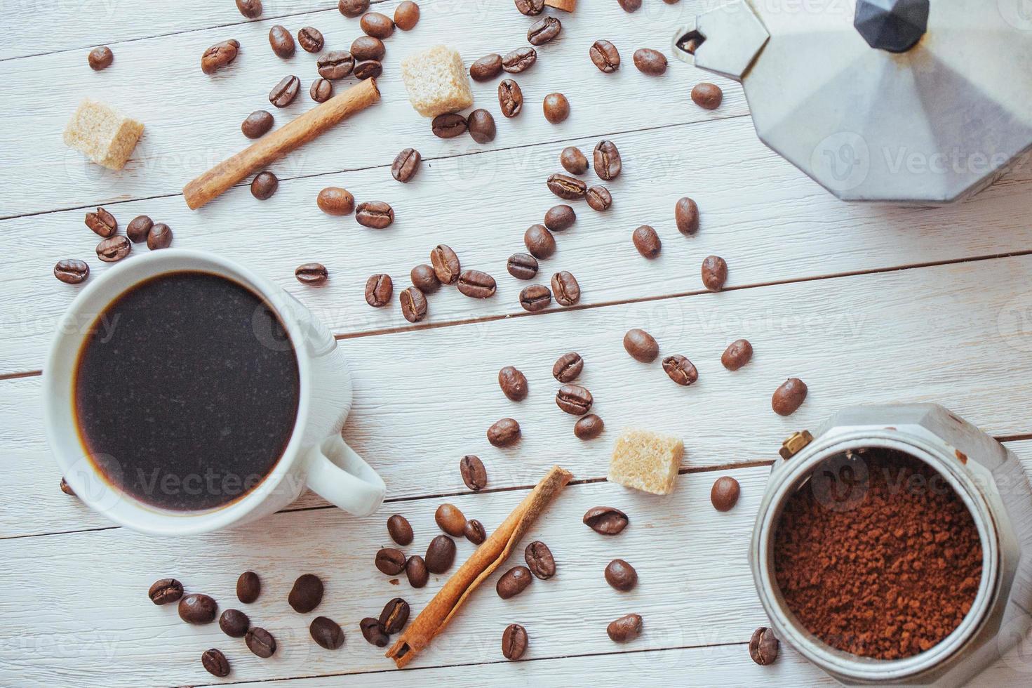 granos de café y una taza de café en la mesa al fondo foto