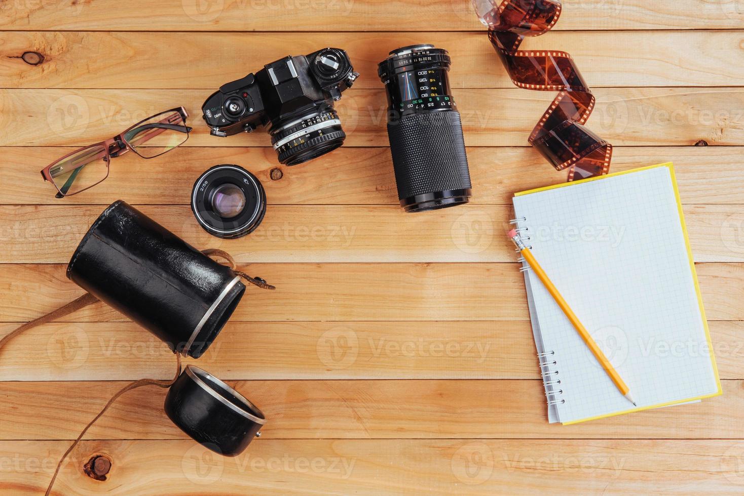 The old film camera and roll film and notebook with pencil on a wooden background photo