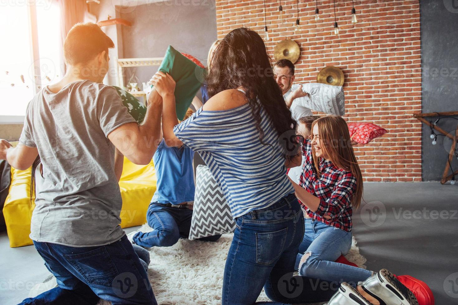 locos jóvenes mejores amigos peleando con almohadas en casa. grupo de personas de raza mixta. concepto de entretenimiento y estilo de vida foto