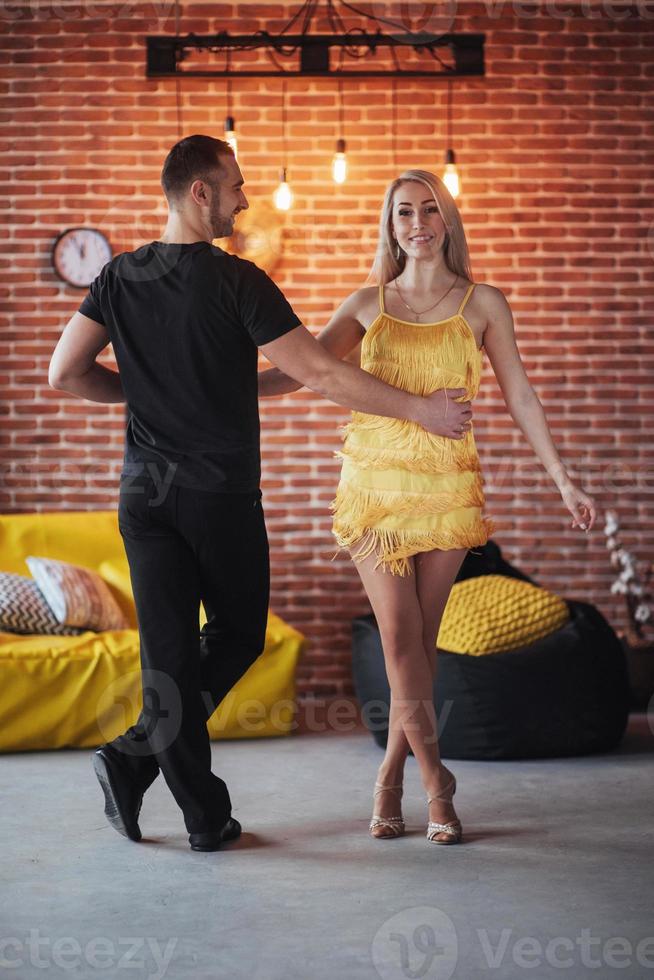 Young couple dancing latin music Bachata, merengue, salsa. Two elegance pose on cafe with brick walls photo