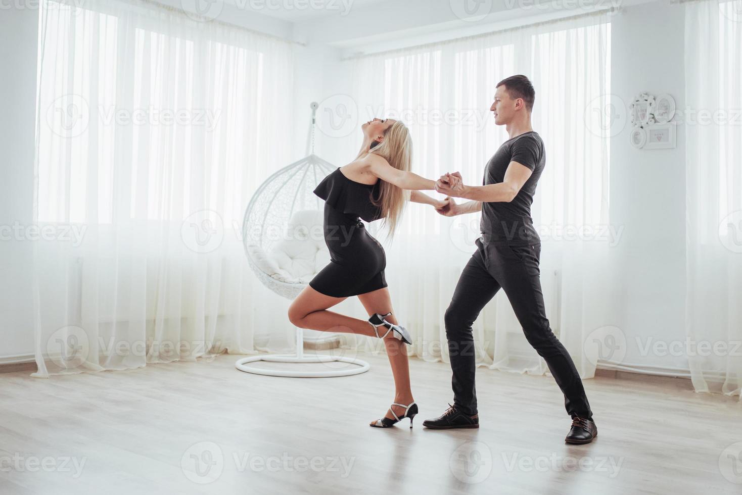 Young couple dancing latin music. Bachata, merengue, salsa. Two elegance pose on white room photo