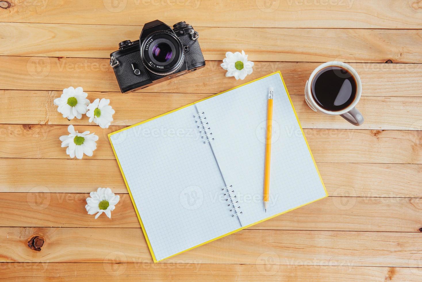 sobre fondo de madera cuaderno lápiz, café y flores. foto