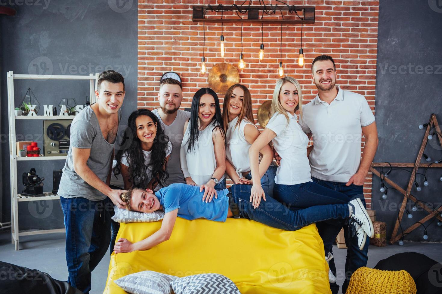 Group portrait of multi-ethnic boys and girls with colorful fashionable clothes holding friend posing on a brick wall, Urban style people having fun, Concepts about youth togetherness lifestyle photo