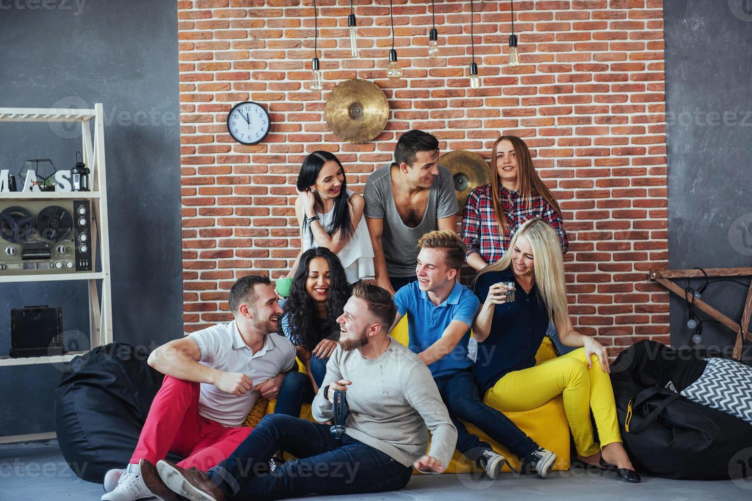 Group portrait of multi-ethnic boys and girls with colorful fashionable clothes holding friend posing on a brick wall, Urban style people having fun, Concepts about youth togetherness lifestyle photo