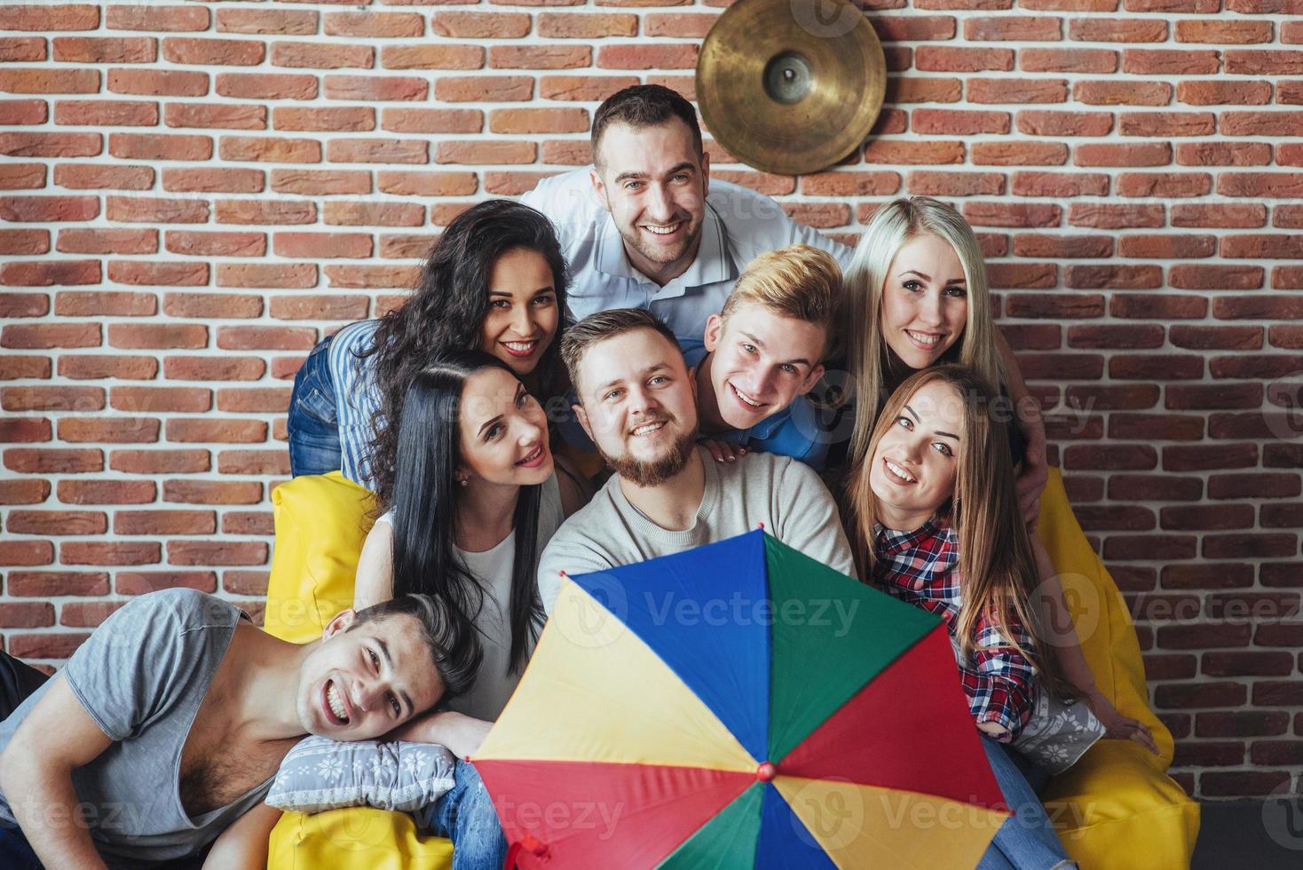 Group portrait of multi-ethnic boys and girls with colorful fashionable clothes holding friend posing on a brick wall, Urban style people having fun, Concepts about youth togetherness lifestyle photo