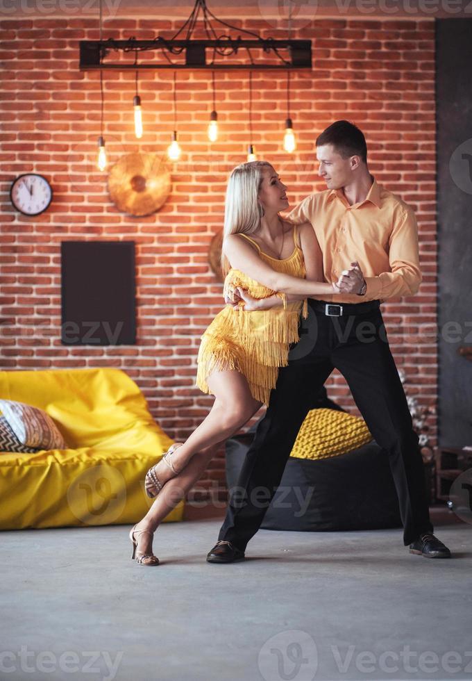 Young couple dancing latin music. Bachata, merengue, salsa. Two elegance pose on cafe with brick walls photo