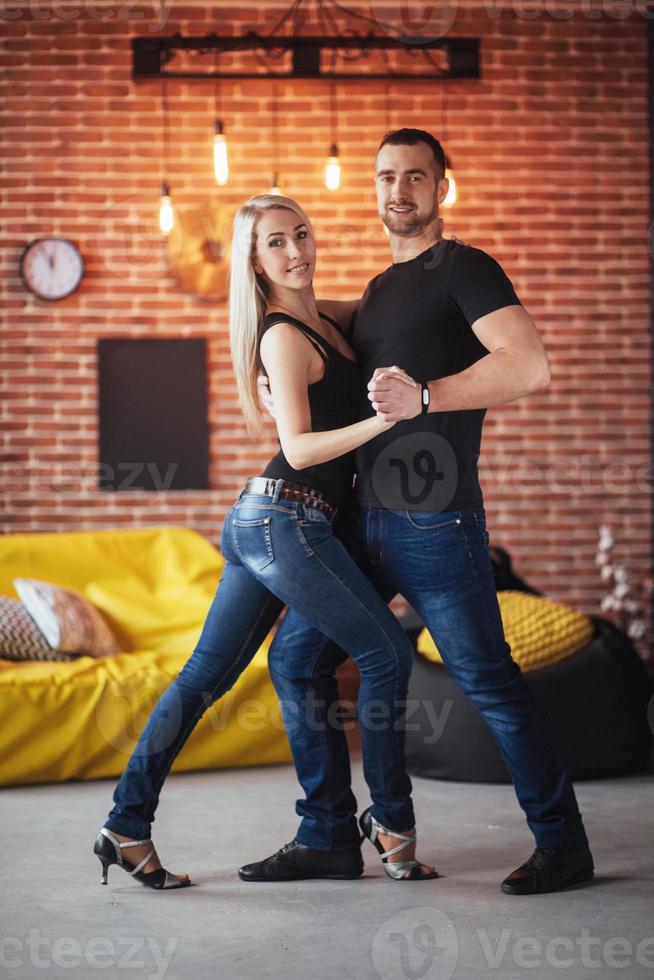 Young couple dancing latin music Bachata, merengue, salsa. Two elegance pose on cafe with brick walls photo