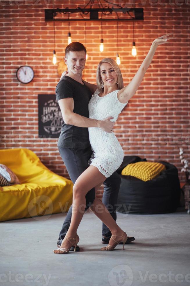 pareja joven bailando música latina. bachata, merengue, salsa. pose de dos elegancia en el café con paredes de ladrillo foto