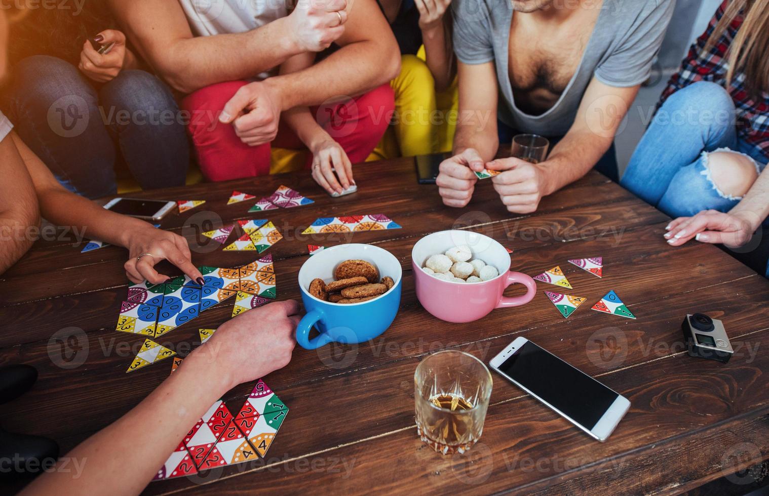 Top view creative photo of friends sitting at wooden table.  having fun while playing board game