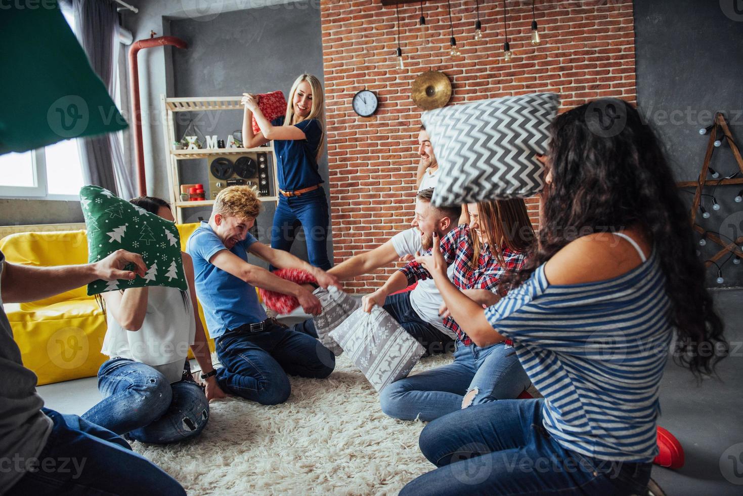 Crazy young best friends fighting pillows at home. Mixed race group of people. Concept  entertainment and lifestyle photo