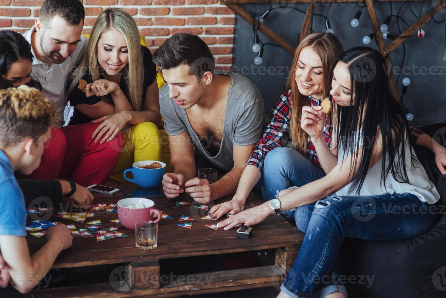 grupo de amigos creativos sentados en la mesa de madera. gente divirtiéndose mientras juega al juego de mesa. foto