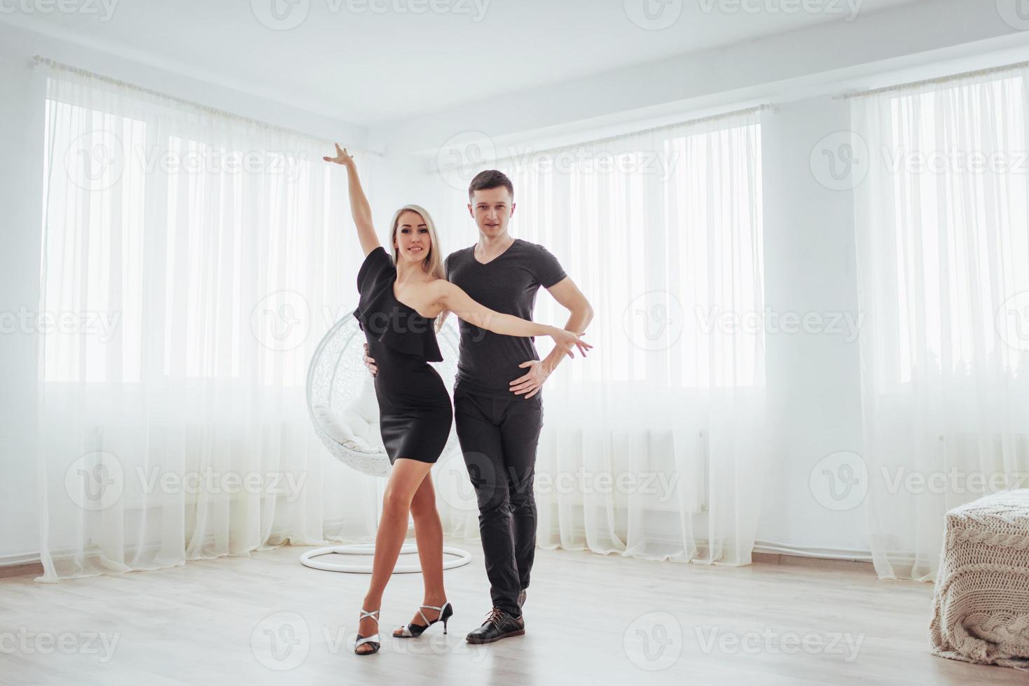 Young couple dancing latin music. Bachata, merengue, salsa. Two elegance pose on white room photo