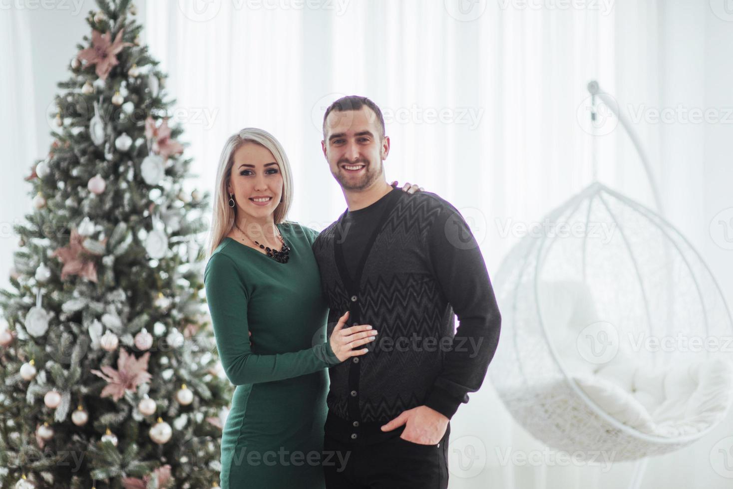 feliz pareja joven en navidad, hermosos regalos y árbol en el fondo foto