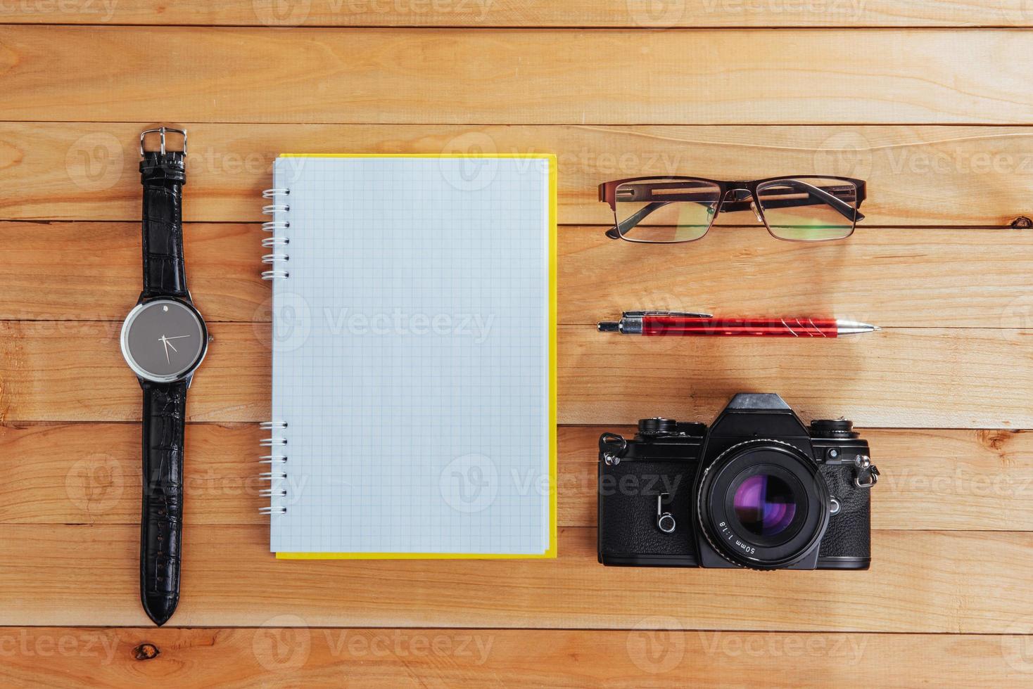 clock, camera and notebook on a brown background photo