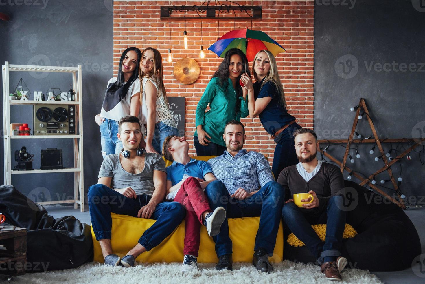Group portrait of multi-ethnic boys and girls with colorful fashionable clothes holding friend posing on a brick wall, Urban style people having fun, Concepts about youth togetherness lifestyle photo