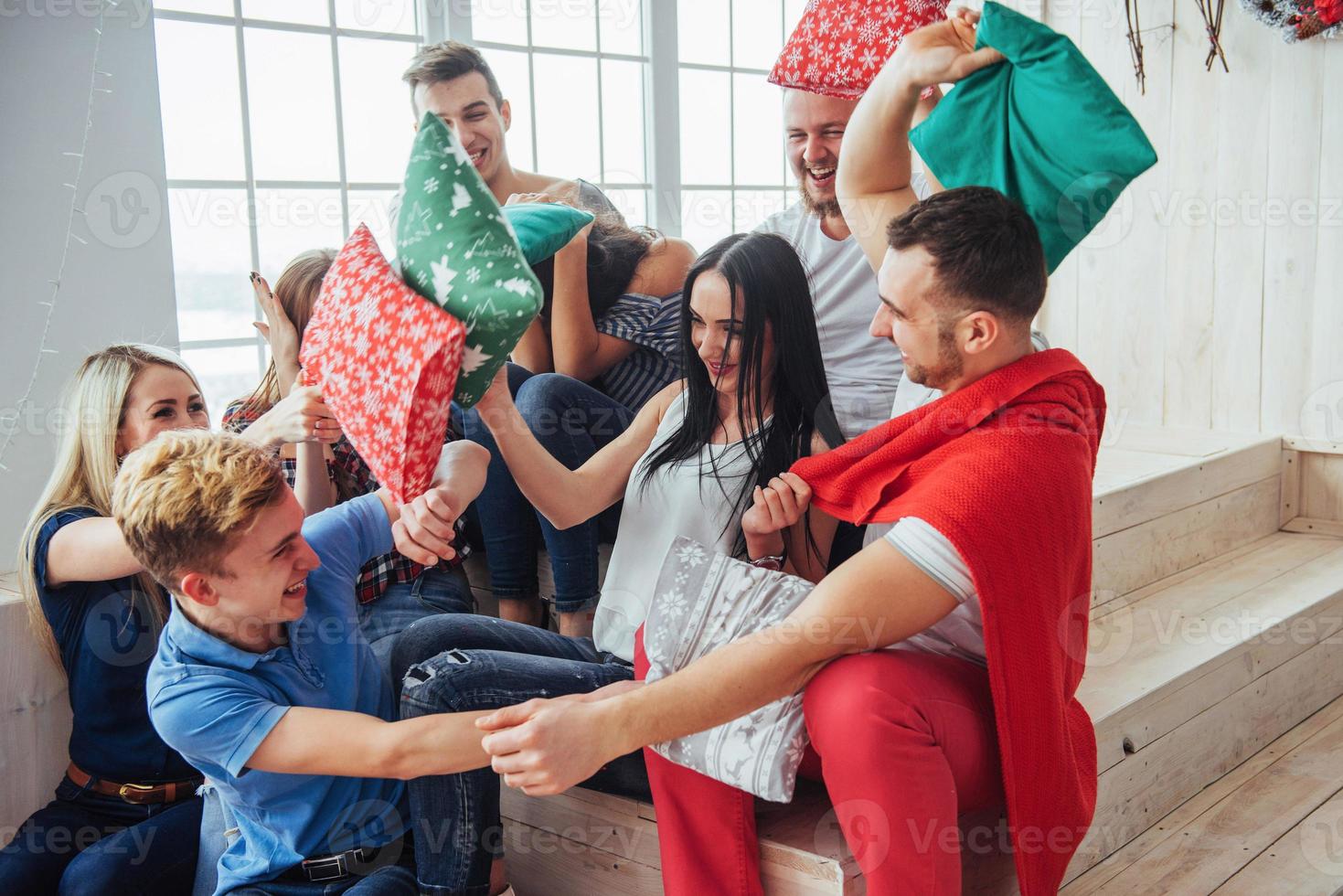 Crazy young best friends fighting pillows at home. Mixed race group of people. Concept  entertainment and lifestyle photo